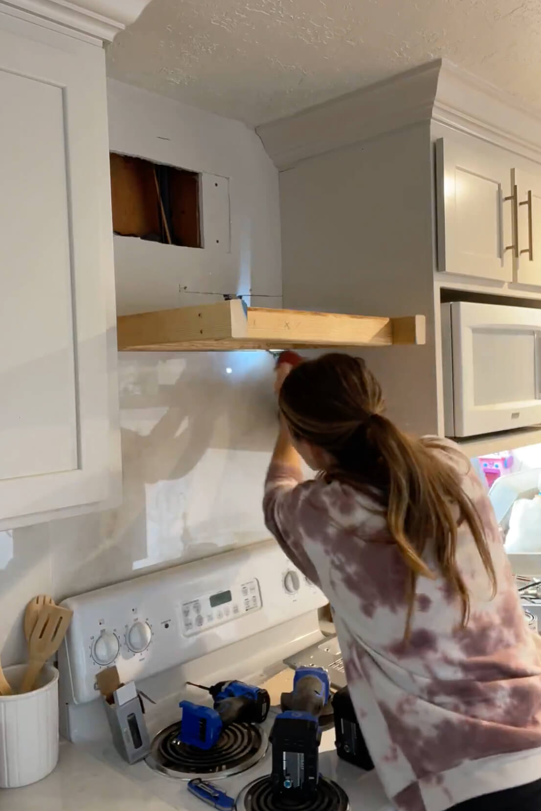 Attaching a range hood frame to the wall studs.